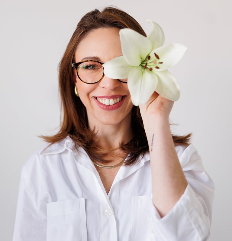 Tatiane amaro segurando uma flor em frente ao rosto.