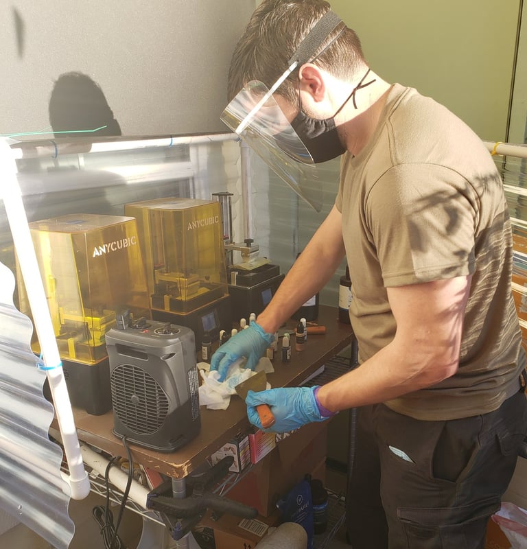 Pictured: Our founder operating three resin 3D printers to produce our first design project (2021).