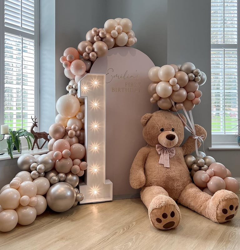 a teddy bear sitting on a table with balloons and balloons