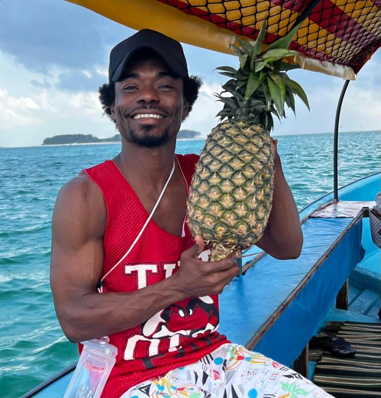 Local tour guide on a Mnemba Island Zanzibar day trip boat tour holding a fresh pineapple for tourists