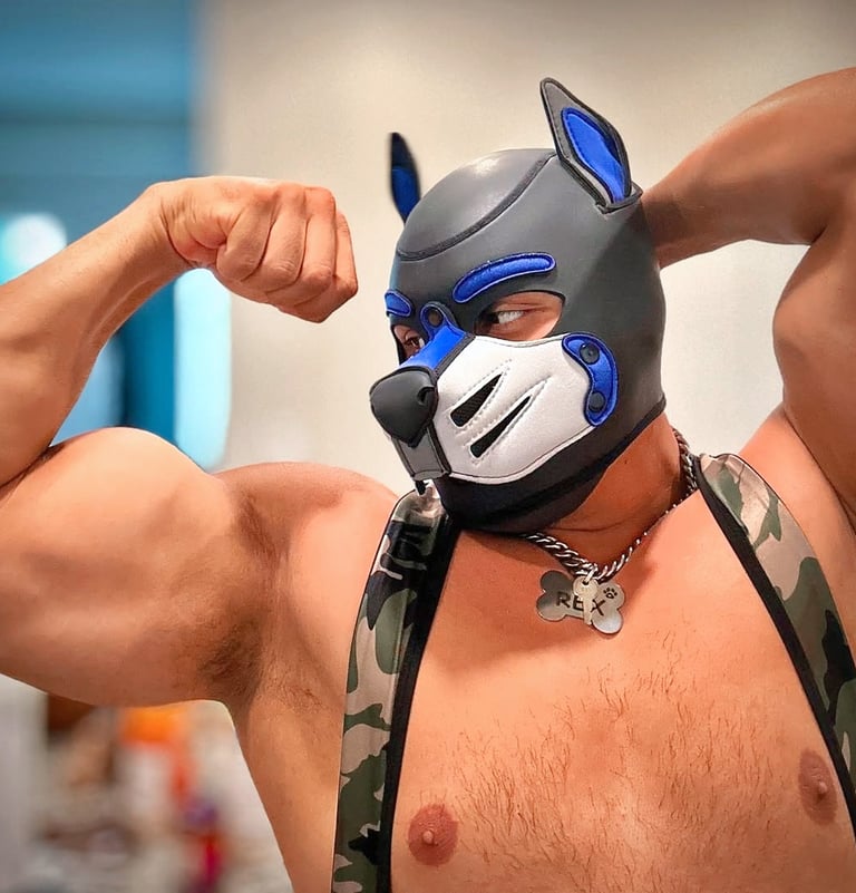 A man fleses while posing in his pup mask.