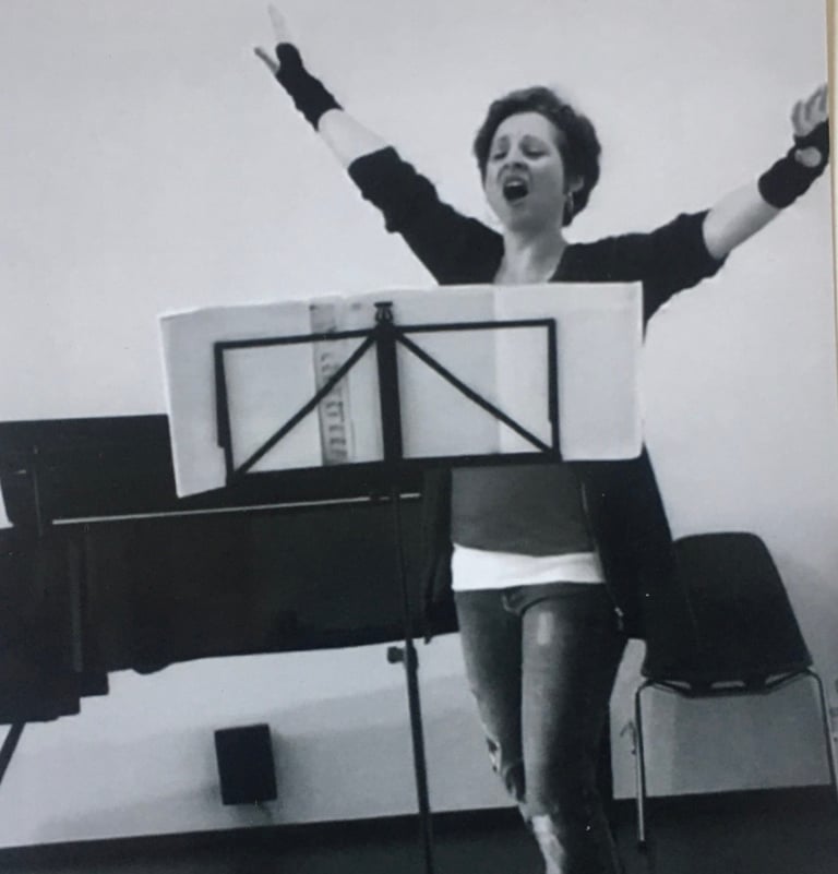 eine junge Frau - Sina Weidlich - singt, die Arme hoch erhoben, im Hintergrund ein Flügel