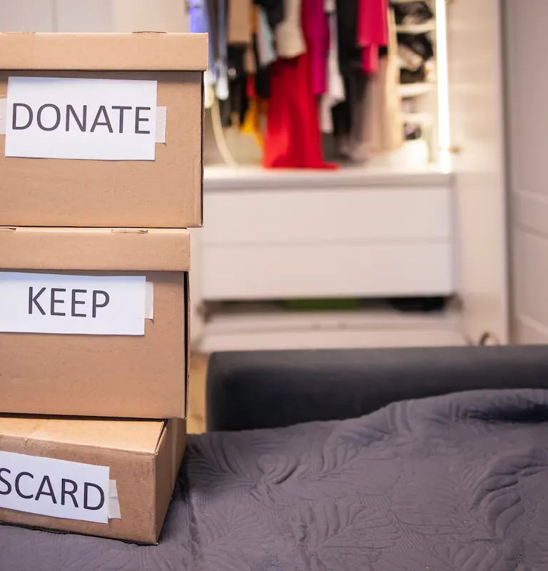 Cardboard boxes labeled donate, keep, and discard for closet organization and home decluttering.