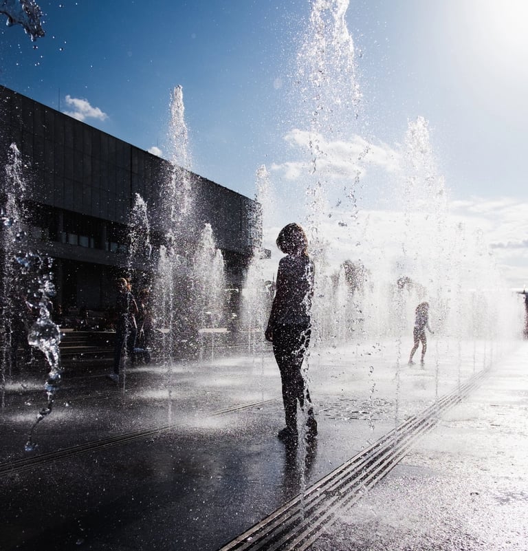 Silhouetted Girl standing in fountain in summer