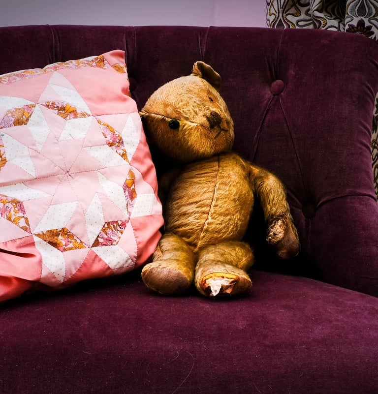 Teddy bear and patchwork cushion on purple velvet chair