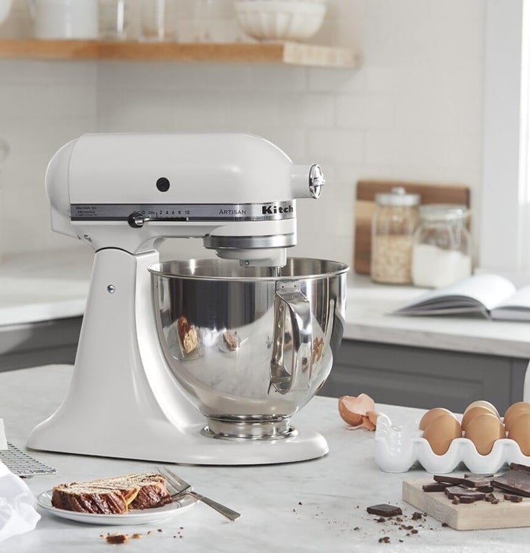 White KitchenAid stand mixer on a kitchen countertop with mixing bowl