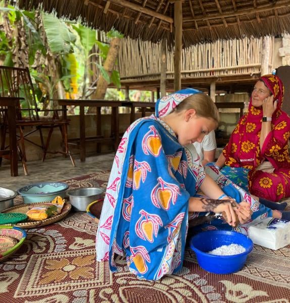 Tourist learning how to crack mature coconut (nazi) with traditional tools during a luxury Zanzibar spice tour with local