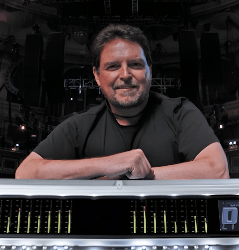 Jon Lemon smiling  and leaning on mixing desk.