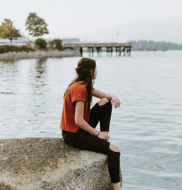 Jeune femme assise sur un rocher au bord d'un lac