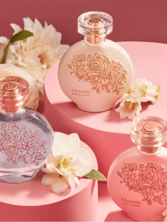 Elegant Floratta perfume bottles with floral engravings on pink pedestals with white flowers.