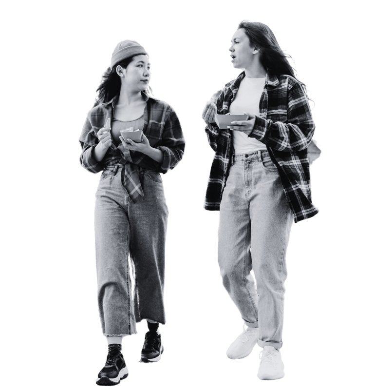 Two women walking with trays of food