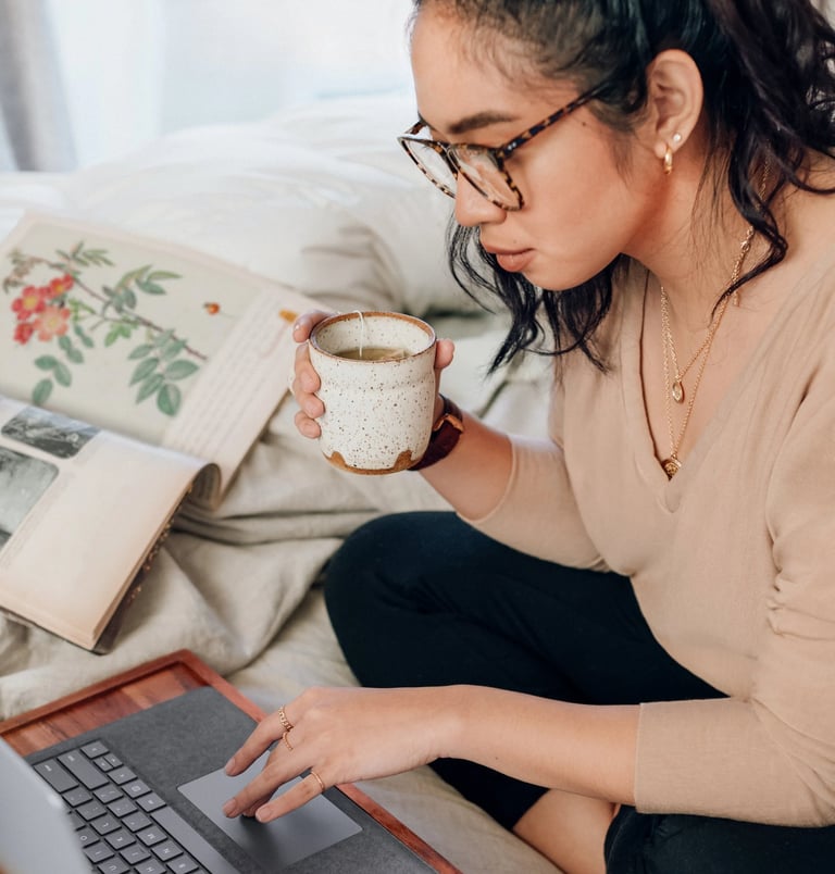 Woman drinking tea in front of computer