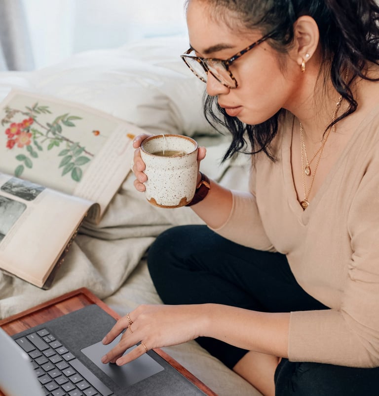 Woman drinking tea in front of computer