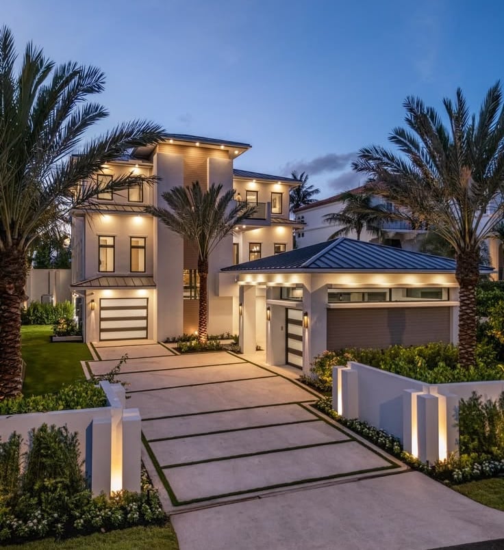 Modern luxury home exterior with glass walls, stone accents, and landscaped driveway