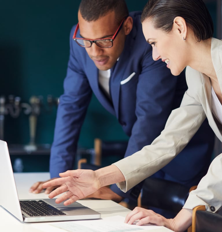 a man and woman looking at a laptop computer