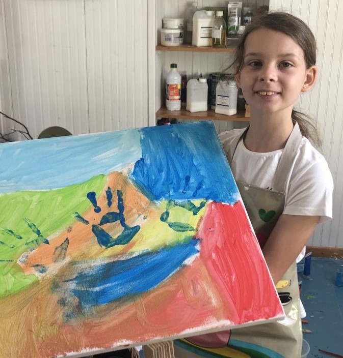Photo de Magali STrassel, art-thérapeute, montrant une petite fille fière de montrer sa peinture