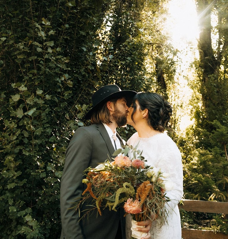 Romantic wedding couple kissing in natural greenery garden setting