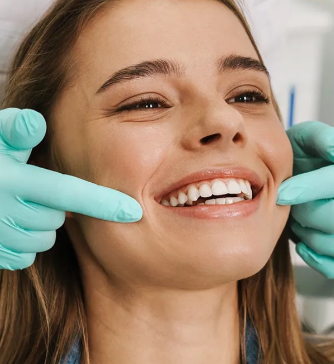 Smiling woman receiving a professional dental checkup for teeth whitening and oral health.
