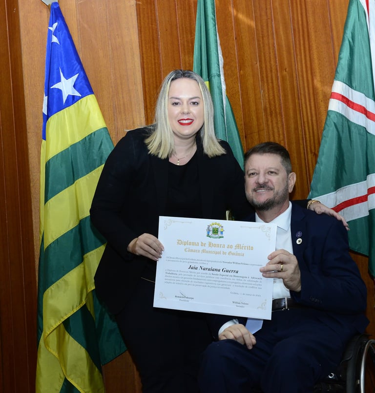 um homem em uma cadeira de rodas entregando um certificado para uma mulher
