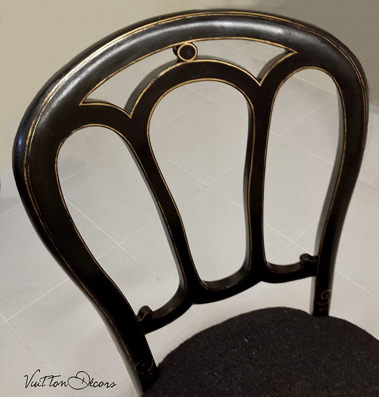Détail d'une chaise bistrot en bois dont la peinture a été restaurée avec ses filets dorés.