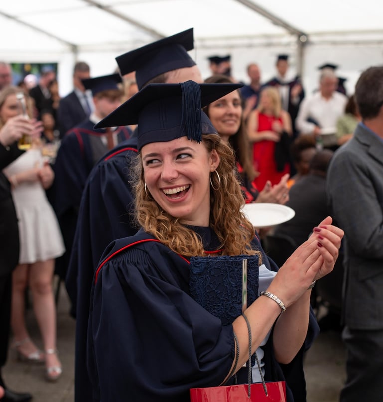 Graduation event photo of a smiling graduate in cap and gown