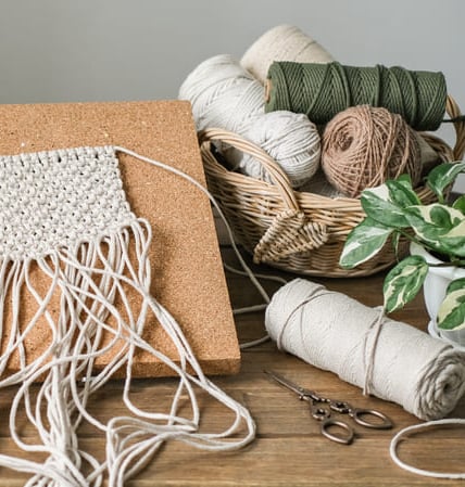 Proyecto de colgante de pared de macramé hecho a mano, fijado a un tablero de corcho.