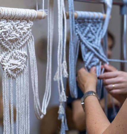 Proyecto de arte colgante de pared de macramé hecho a mano en progreso sobre un perchero de metal.