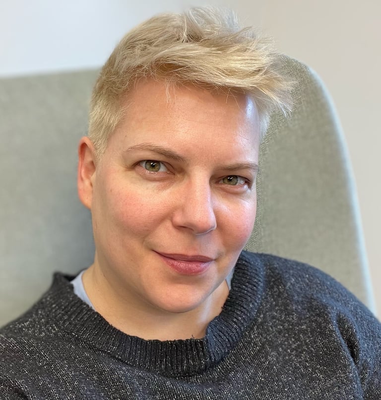 A woman with short bleached hair and a blue-gray sweater