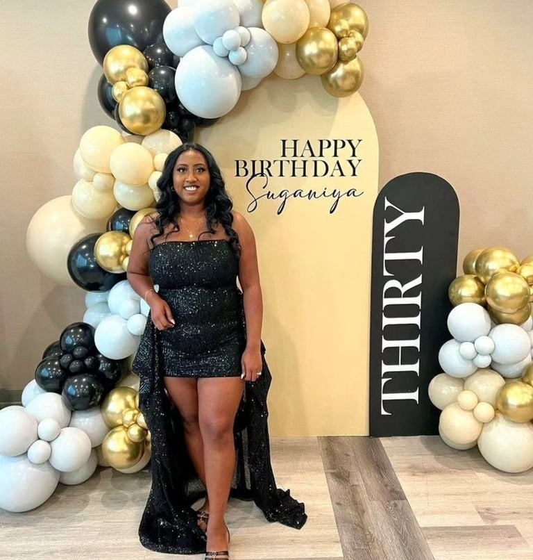 a woman in a black dress standing in front of a birthday sign