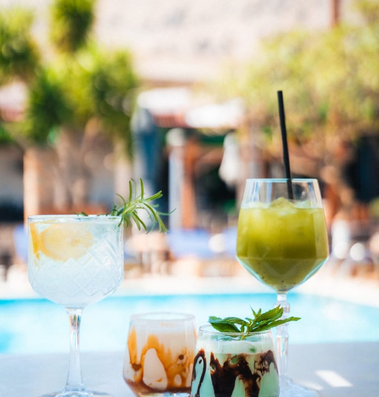 Refreshing summer cocktails and iced coffee drinks served on a patio table by Luxury swimming pool.