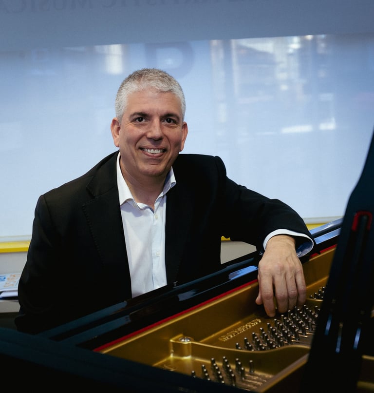 a man in a suit and tie smiling at the camera with baby grand piano