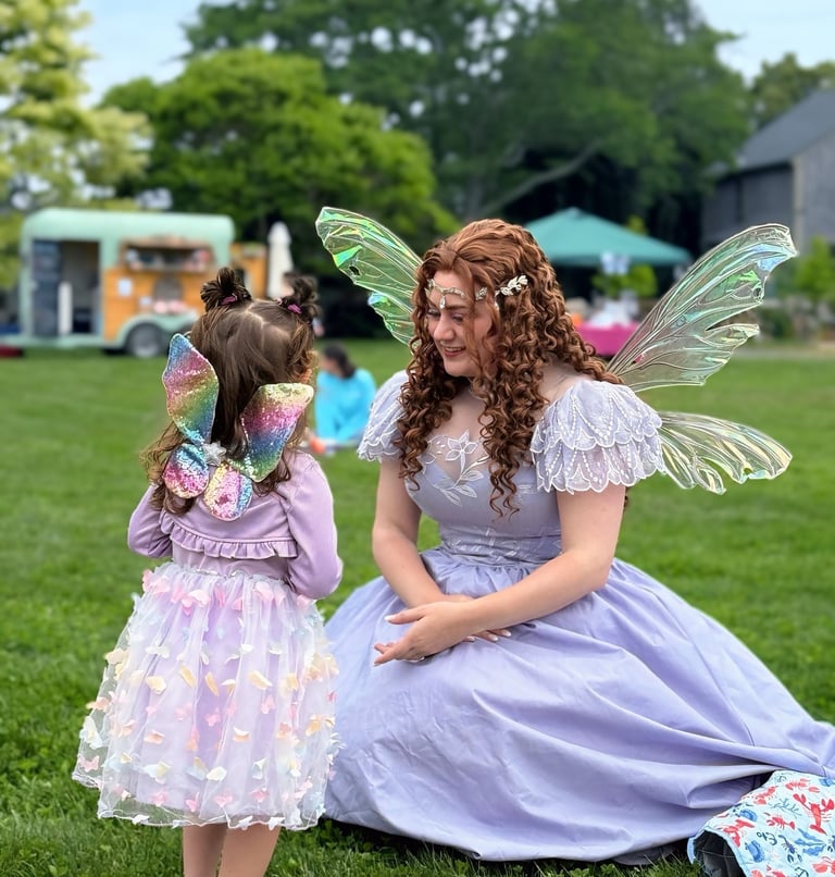 Purple fairy smiles at a kid also dressed as a fairy