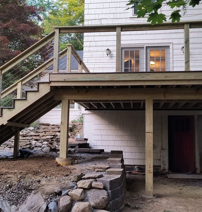 Custom wood deck with outdoor seating overlooking a wooded backyard landscape