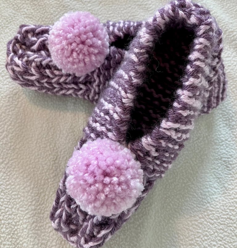 Pair of hand knitted purple slippers with light lavander pompoms