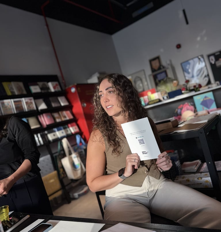 Judy sits in a bookstore holding up a designed card