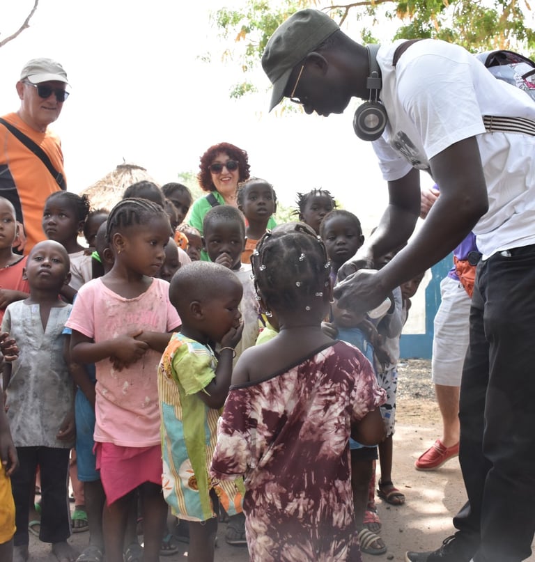 Dahomey African Tours Guide leading Tourists and giving gifts to Children in Senegal