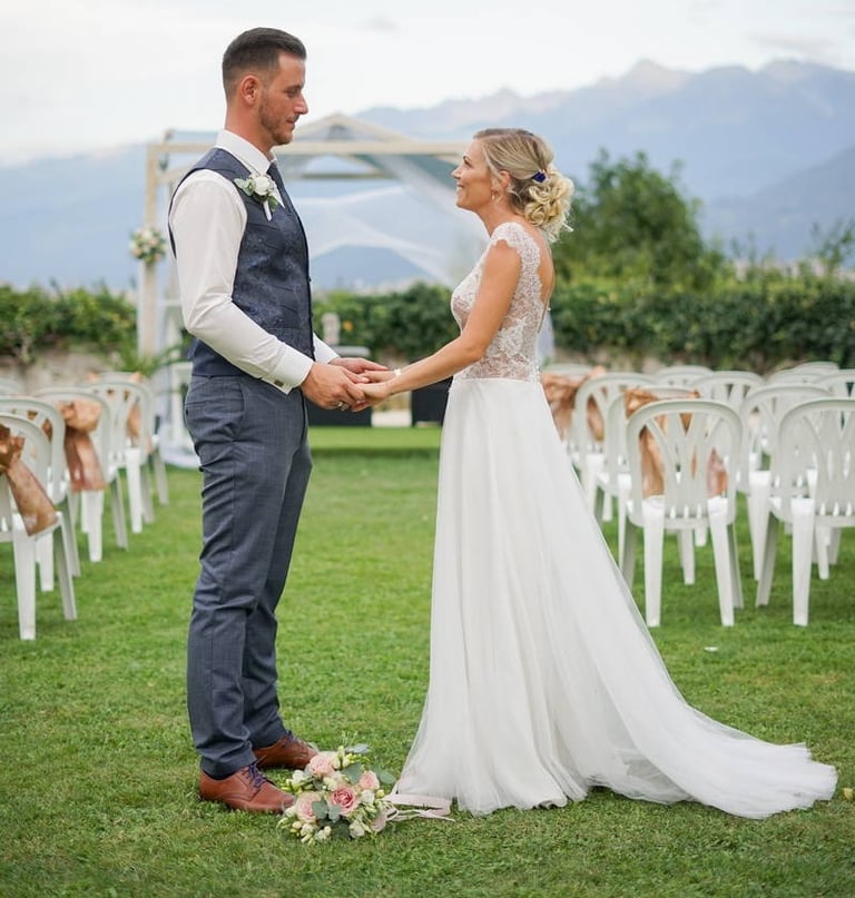Photo d'un couple de mariés face à face se tenant la main sur le lieux de leur cérémonie de mariage