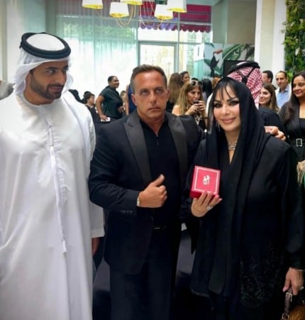 A group of people stand together at a Bedig Minassian event, with some holding phones to take photos