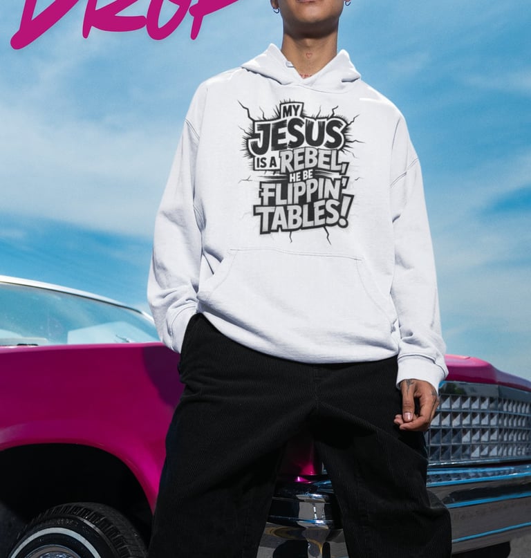A man wearing a white christian streetwear hoodie with a Jesus is a rebel graphic, standing by a pink car.