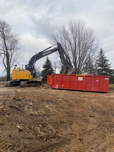 John Deere excavator putting rubble into dumpster