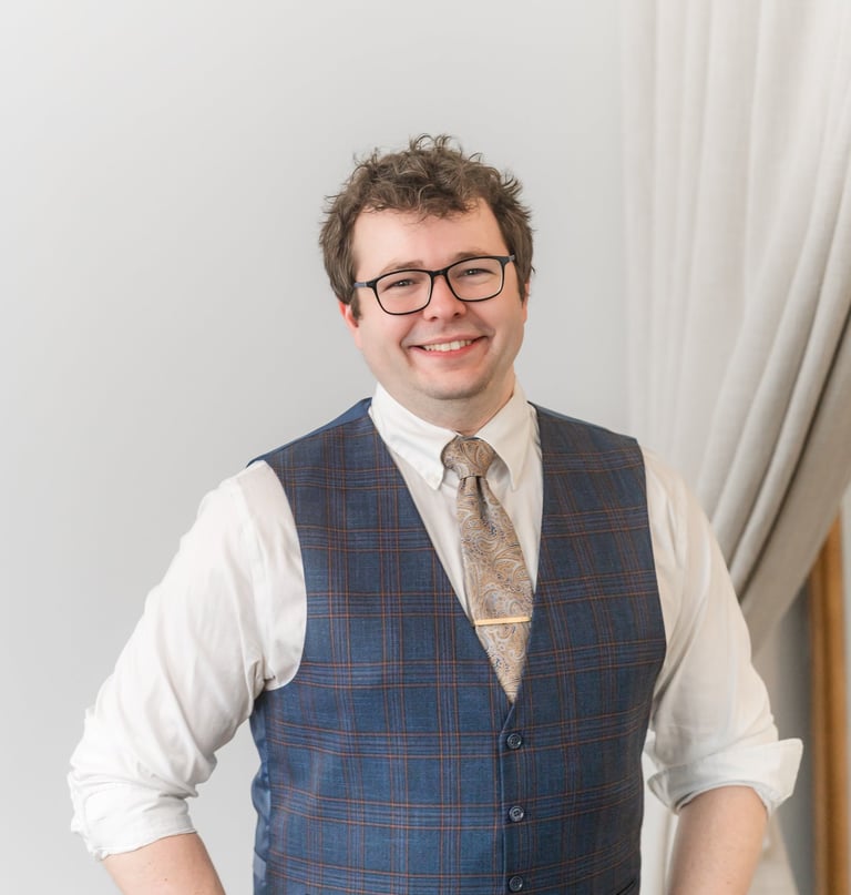 Picture of Rocco Catrone smiling at camera with glasses, a gold tie, and vest.