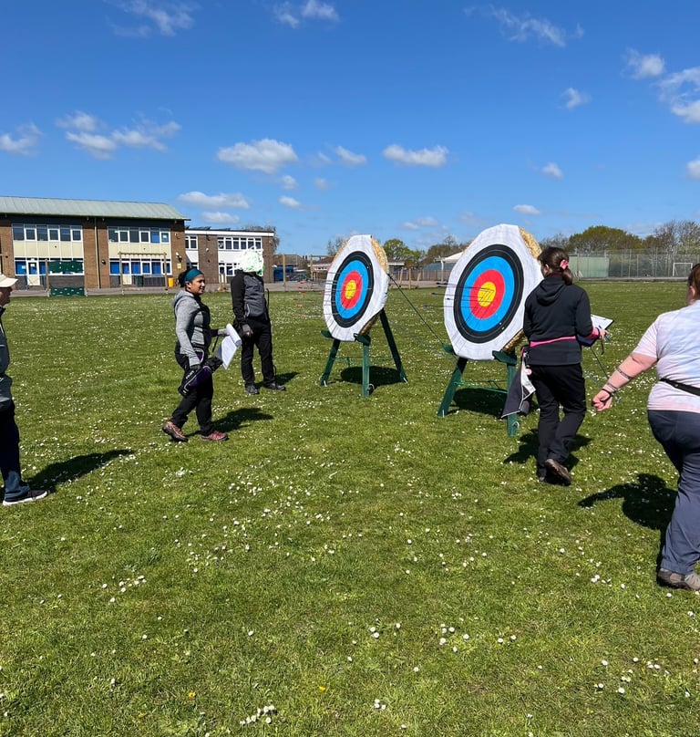 a group of people walking up to an archery target