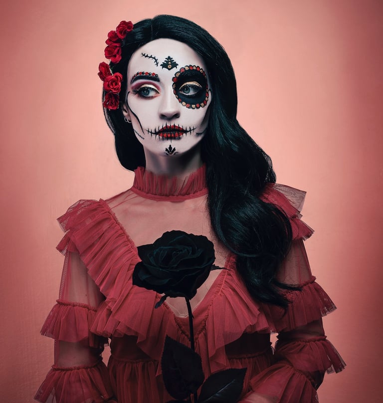 Woman with Dia de los Muertos sugar skull makeup holding a black rose in a red ruffled dress.