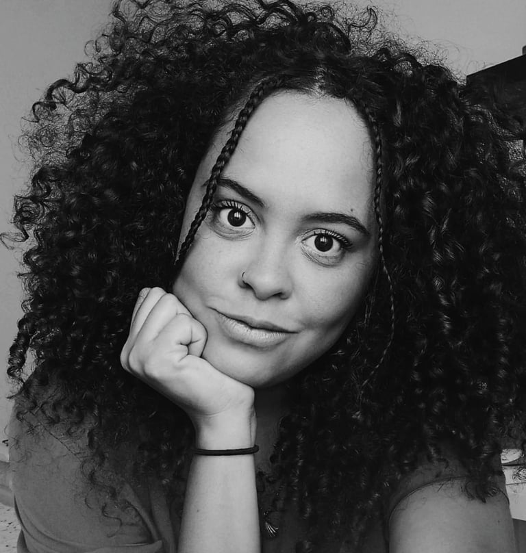 Black and white portrait of a woman with voluminous curly hair and face-framing braids.