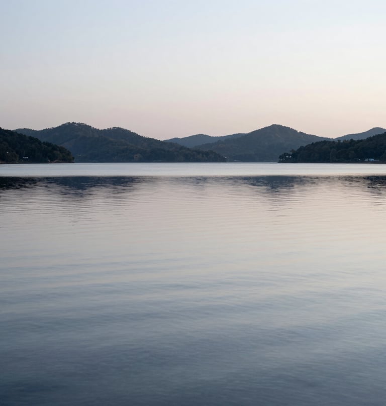 Minimalistic landscape photography of a calm lake at dawn. The water is a smooth, silvery blue-grey, reflecting the silhouette of distant hills under a soft, overcast sky. Pure simplicity and elegance.