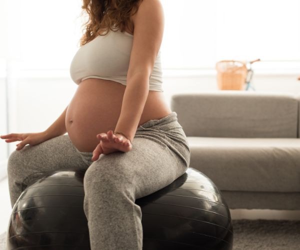a pregnant woman sitting on a ball with her belly