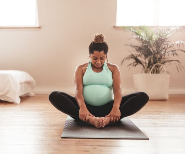 a pregnant woman sitting on a yoga mat