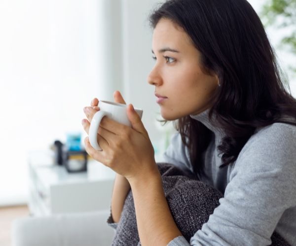 a woman sitting on a couch holding a cup of coffee