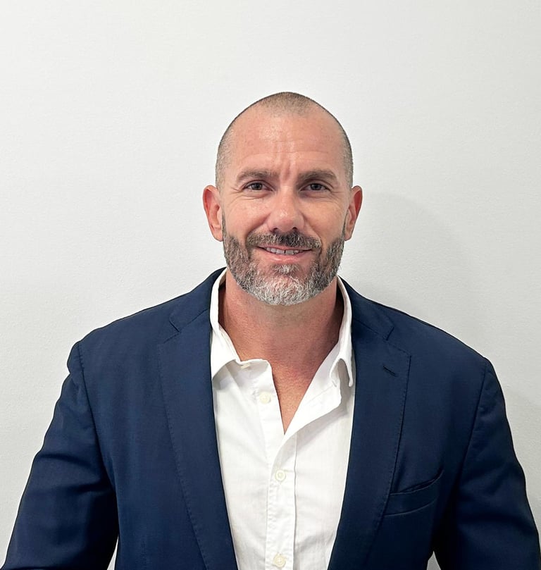 Professional headshot of a smiling middle-aged businessman wearing a navy blue blazer and white shirt.