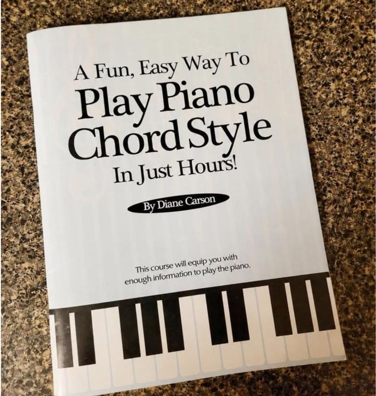 A piano lesson book titled Play Piano Chord Style by Diane Carson sits on a granite countertop.
